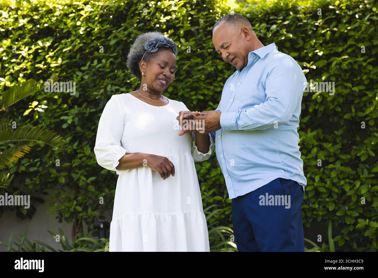 Bei der Hochzeit tauscht ein Seniorenpaar Ringe im Garten aus, um Liebe und Engagement im Freien zu feiern Stockfoto