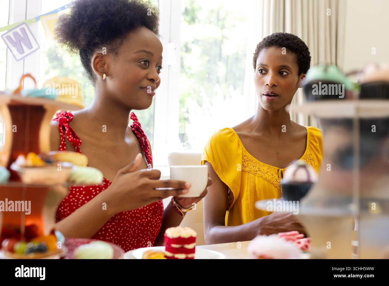 Verschiedene Freundinnen genießen Tee und Desserts und tauschen sich zu Hause aus Stockfoto