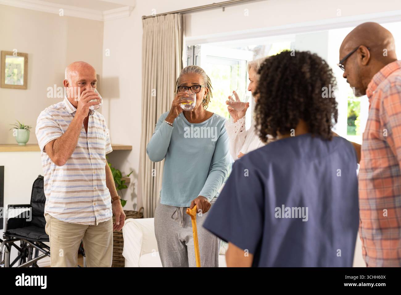 Ältere Freunde, die gemeinsam erfrischende Getränke in gemütlicher Wohnzimmeratmosphäre genießen, zu Hause Stockfoto