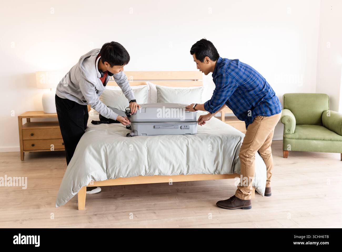 Vater und Sohn packen Koffer im Bett, bereiten sich auf den Familienausflug vor, zu Hause Stockfoto