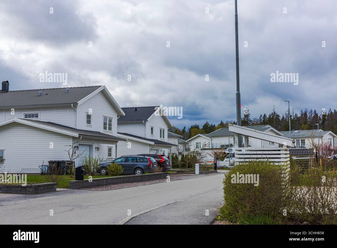 Moderne weiße Häuser mit Autos auf Vorstadtstraße vor dem Hintergrund des bewölkten dramatischen Himmels. Schweden. Stockfoto
