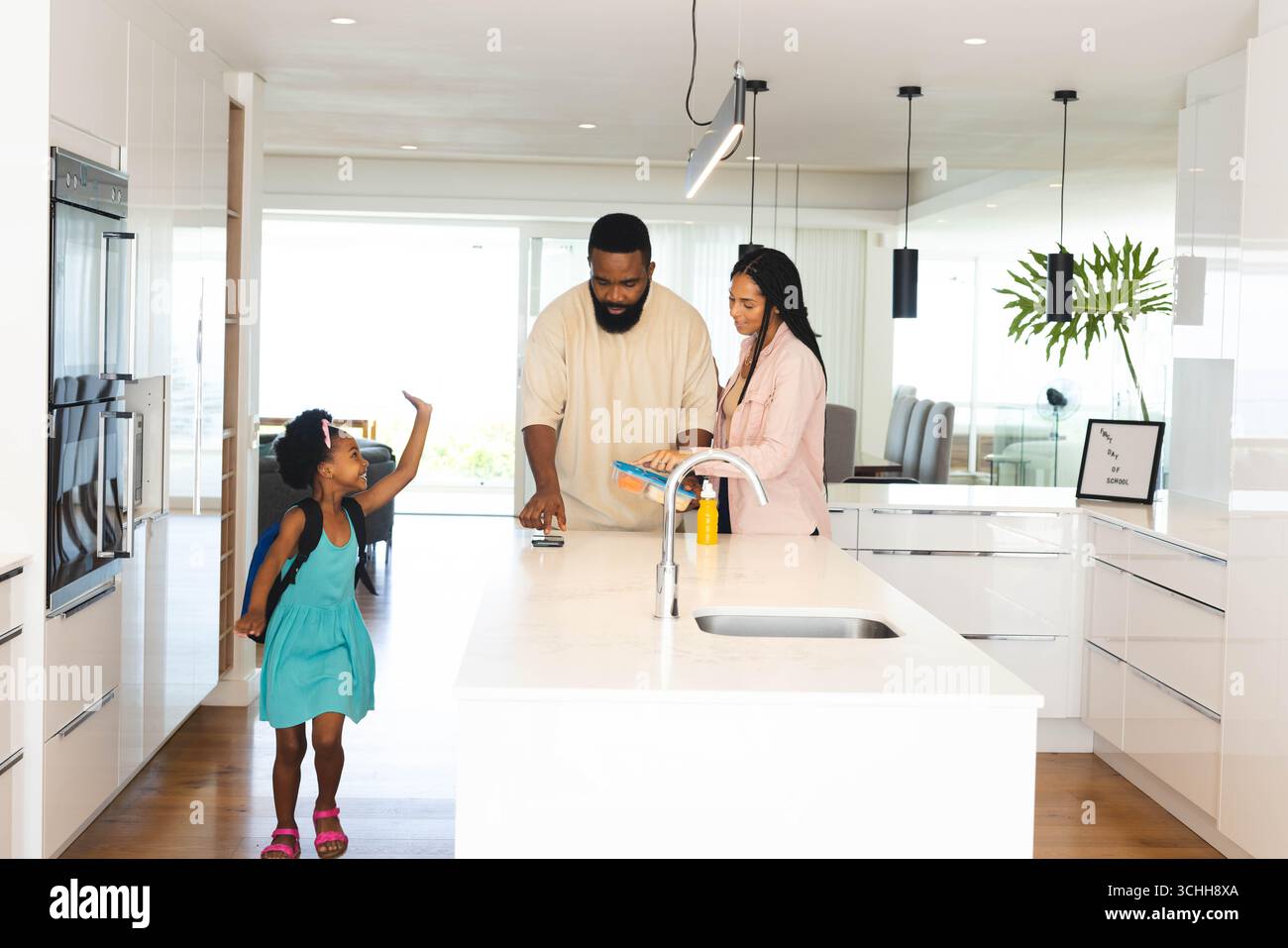 Glückliche Familie, die Zeit in der modernen Küche genießt, glückliche Eltern lesen während Kind spielt, zu Hause Stockfoto