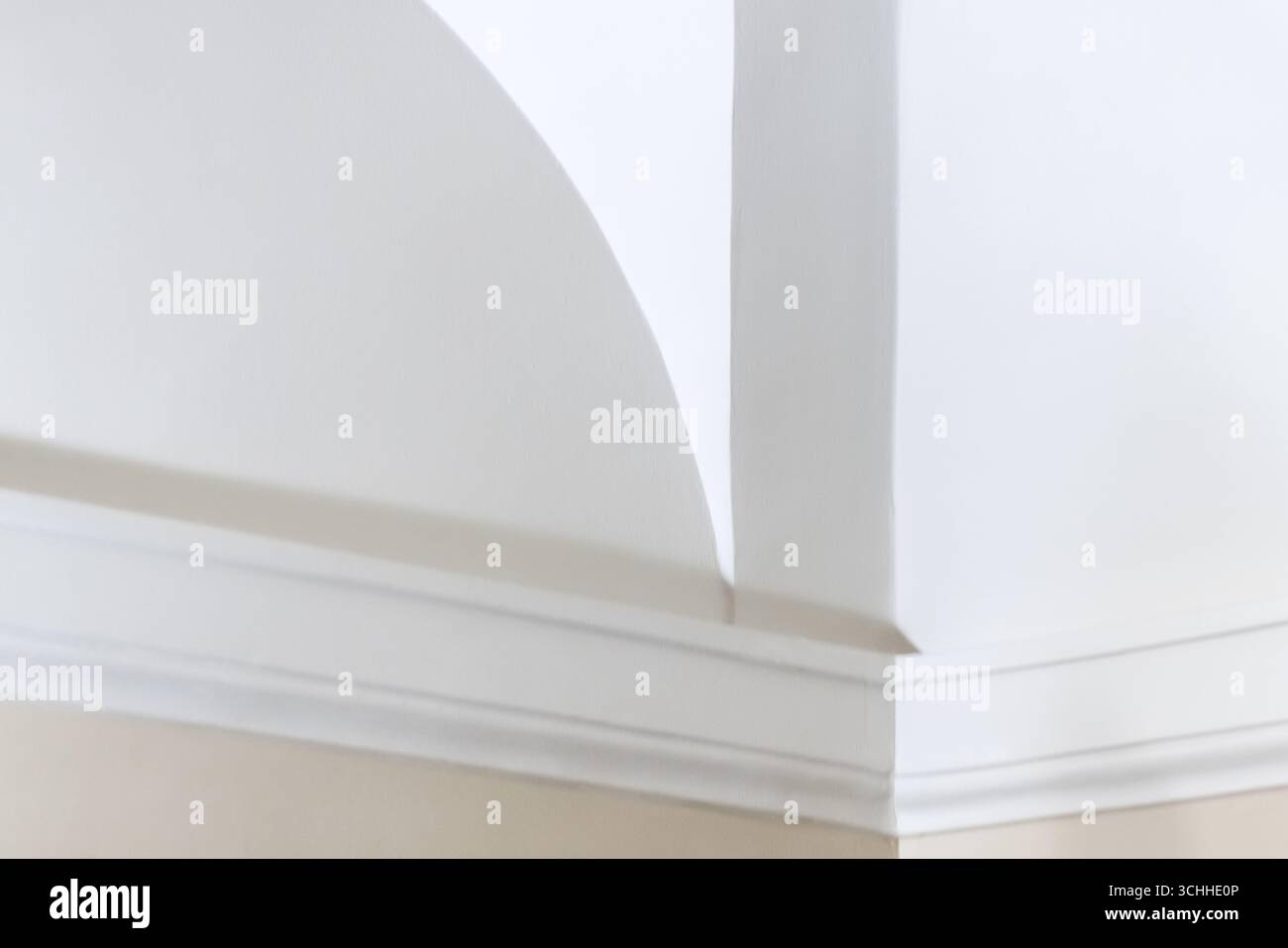 Elegantes, minimalistisches Innendesign mit einer ruhigen weißen Wand mit architektonischen Elementen, darunter gewölbte Ecken und klare Linien, die einen SER schaffen Stockfoto