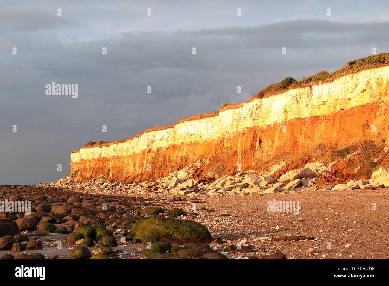 Bunte Klippen am Strand von Hunstanton, gebildet aus Sedimentfelsen verschiedener Art, die in der Abendsonne leuchten. Stockfoto