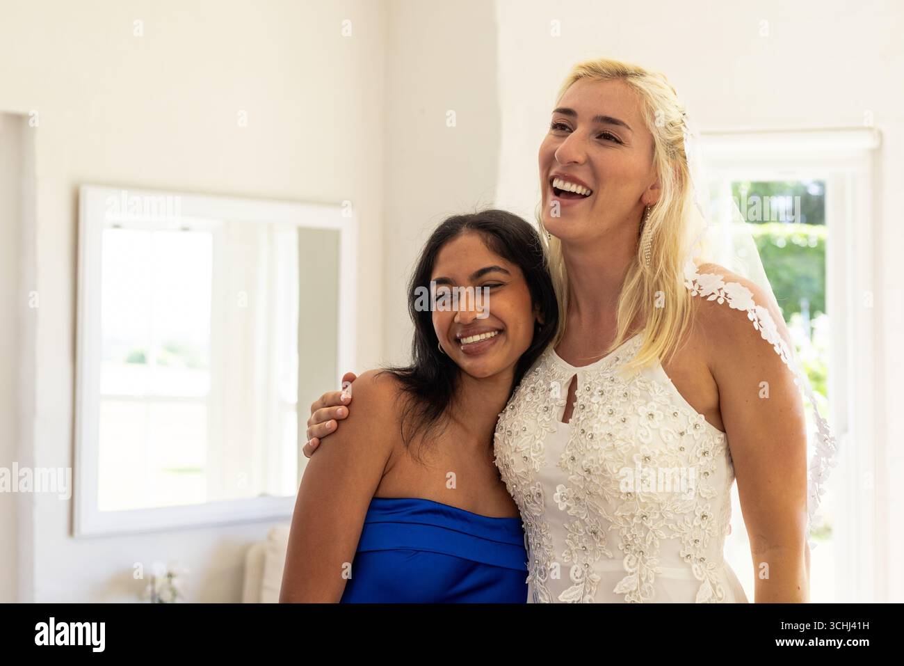 Braut und Freund lächeln fröhlich in eleganter Hochzeitskleidung zu Hause Stockfoto