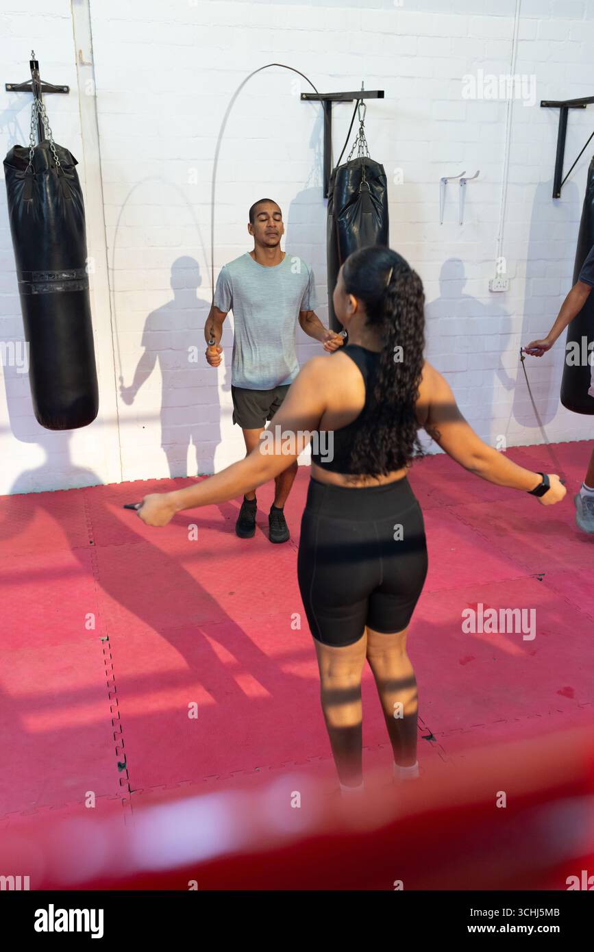 Trainingspartner in Sportbekleidung überspringen Sprungseile auf roten Matten im Studio mit Boxsäcken Stockfoto