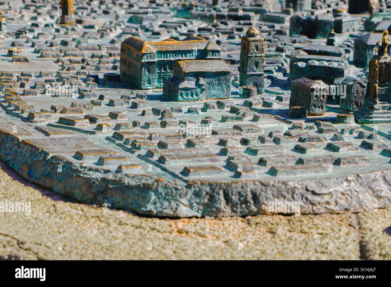 Eine detaillierte Bronze-Relief-Karte stellt das architektonische Layout einer Stadt dar und zeigt bedeutende Bauten und Straßendesigns in lebendigem Sonnenlicht Stockfoto