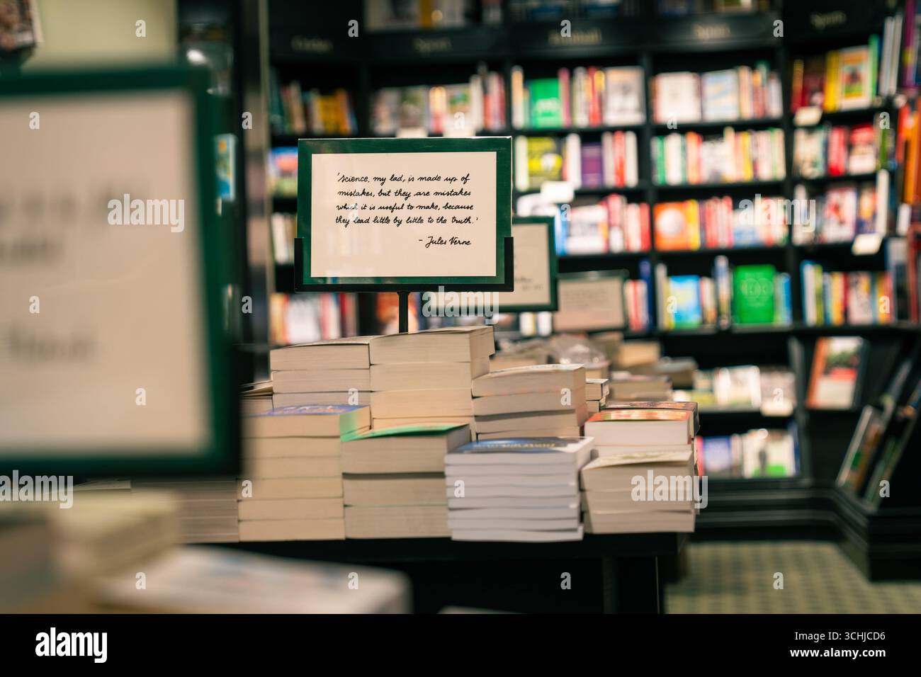 Handgeschriebenes Zitat von Jules Verne über Wissenschaft und Wahrheit auf dem Schild der Buchhandlung, das über einem Stapel von Vintage-Büchern angebracht ist Stockfoto