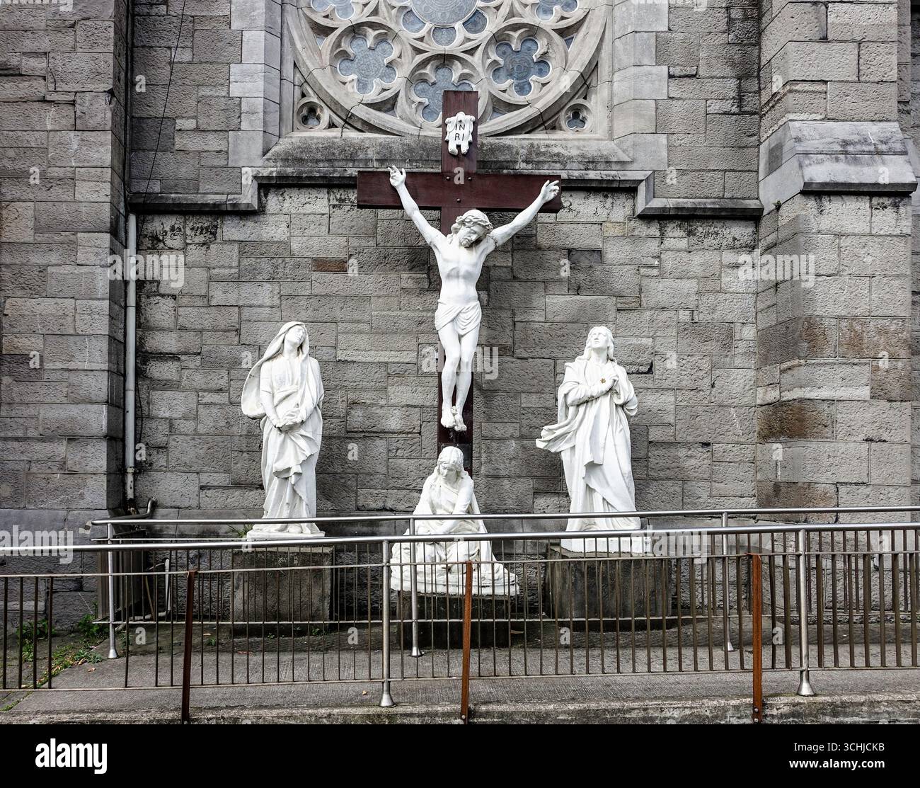 Kreuzigungsszene im Freien in der St. Mary of the Angels Kapuzinerkirche, Church Street, Dublin, mit Statuen von Christus auf dem Kreuz und Figuren darunter. Stockfoto