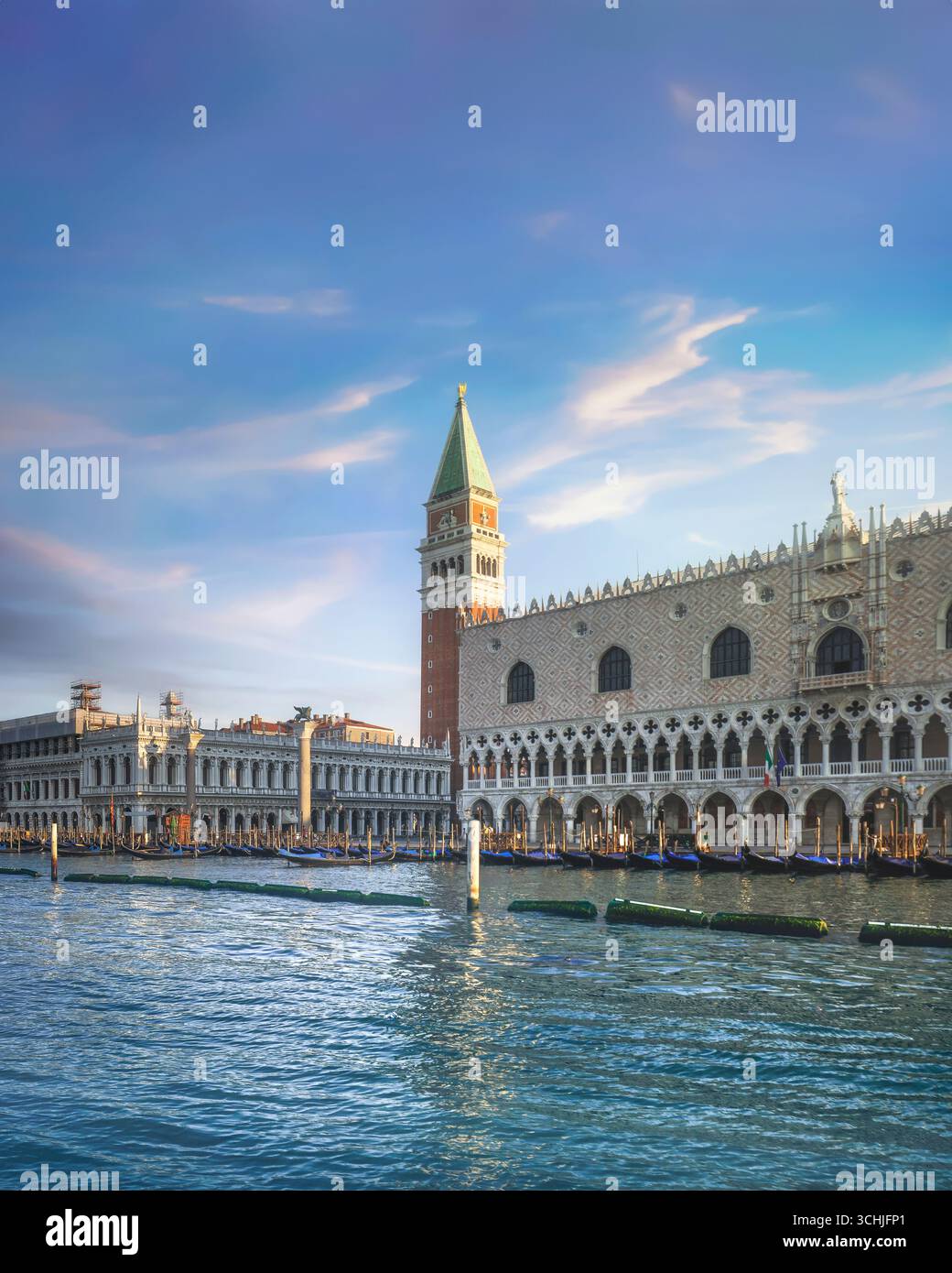 Ikonischer Blick auf Venedig mit Dogenpalastfassade, Markusglocke und Gondeln, die entlang des Canal Grande unter dramatischem Abendhimmel vertäut sind, Region Venetien, Stockfoto