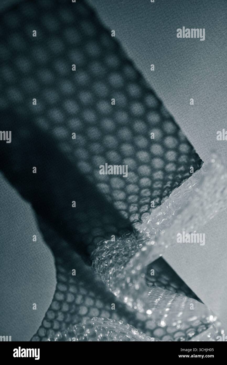 Nahaufnahme der Luftpolsterfolie, die geometrische Schatten auf einer Oberfläche erzeugt. Abstrakte Minimaltextur bei monochromem Licht. Stockfoto