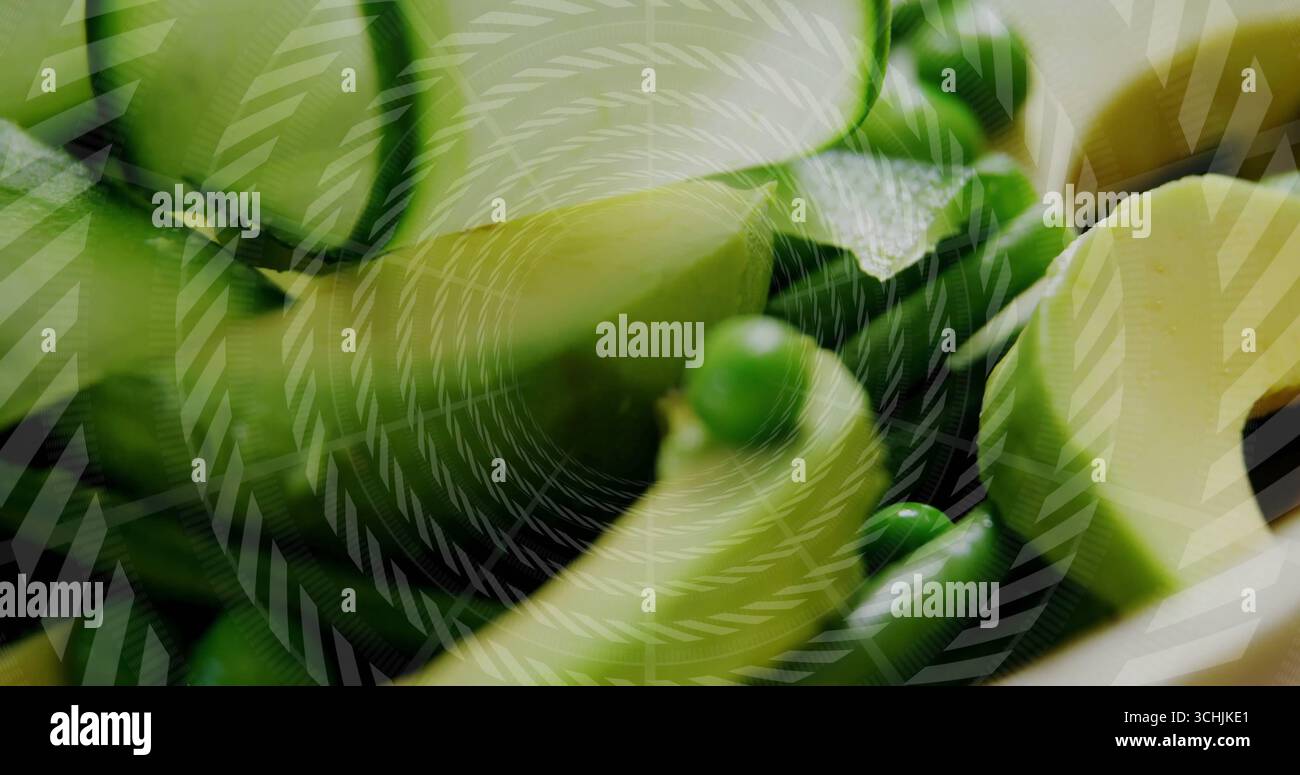 Mit spiralförmigen Gemüsebändern, die sich auf dem Schneidebrett kräuseln, grünen Erbsen und grafischer Überlagerung Stockfoto