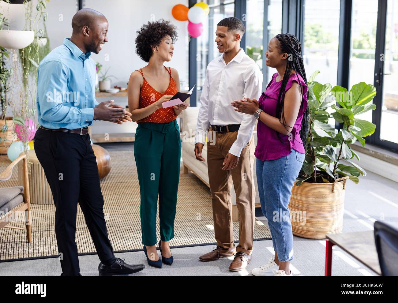 Verschiedene Kollegen im Büro feiern Erfolg, lächeln und halten eine Glückwunschkarte Stockfoto