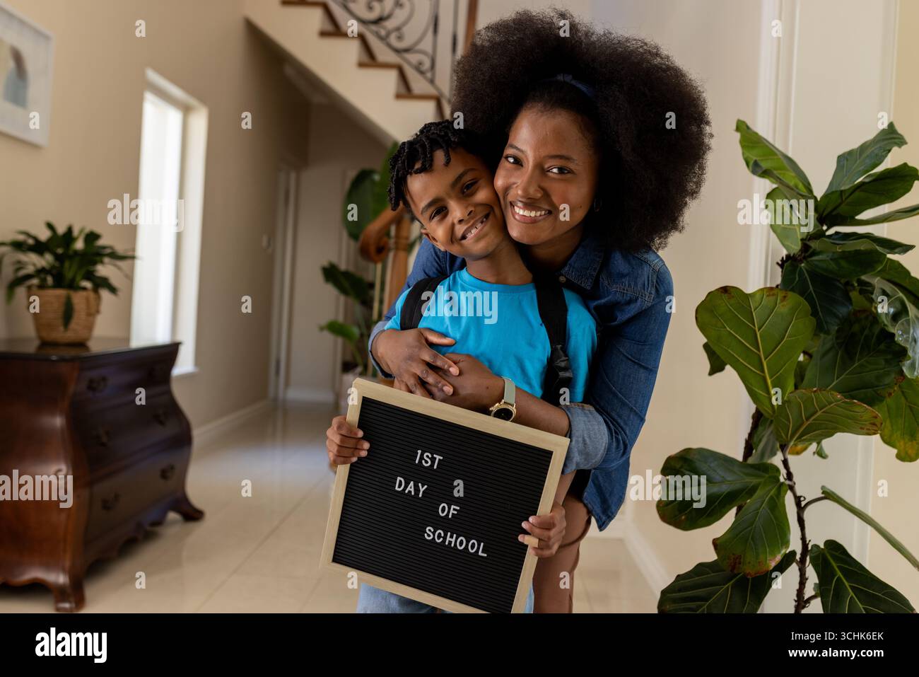 Mutter und Sohn lächeln, Schild für den ersten Schultag zu Hause halten Stockfoto