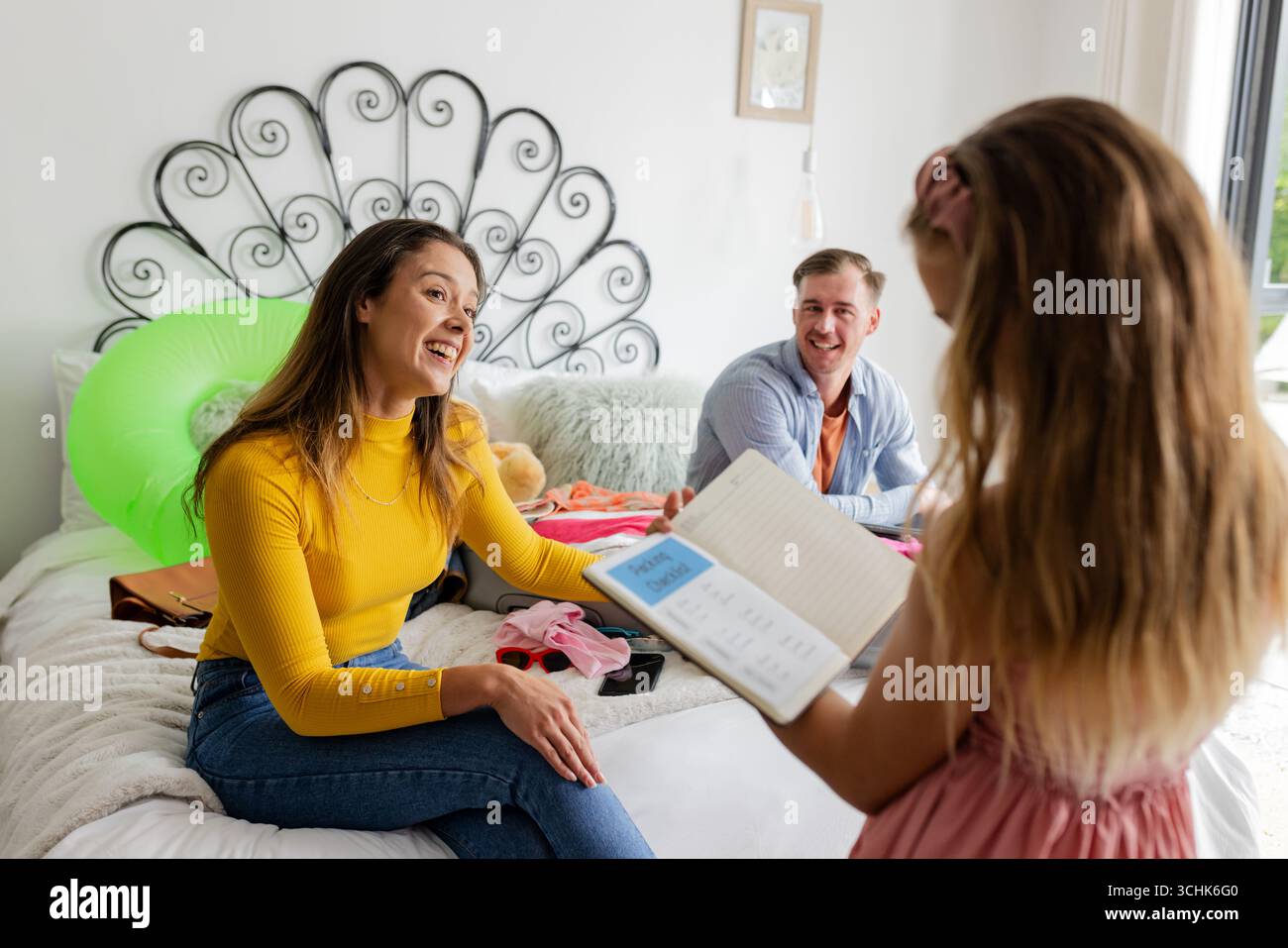 Familie genießt gute gemeinsame Zeit, Tochter zeigt den Eltern im Bett Notizbuch Stockfoto