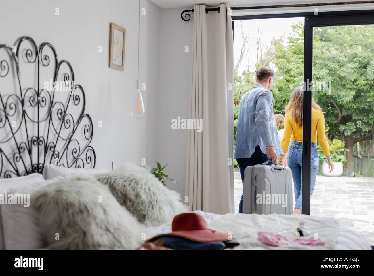 Ein Paar, das mit Koffer zu Hause geht, geht nach draußen, um Abenteuer zu erleben Stockfoto