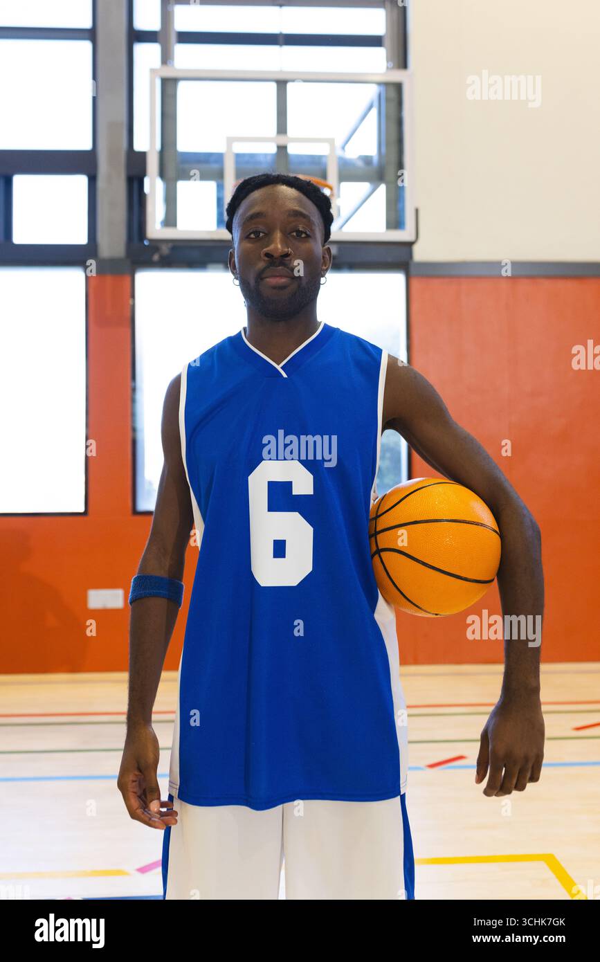 afroamerikaner in blauem Trikot Nummer 6, der orangen Basketball am Basketball auf dem Sportplatz hält Stockfoto