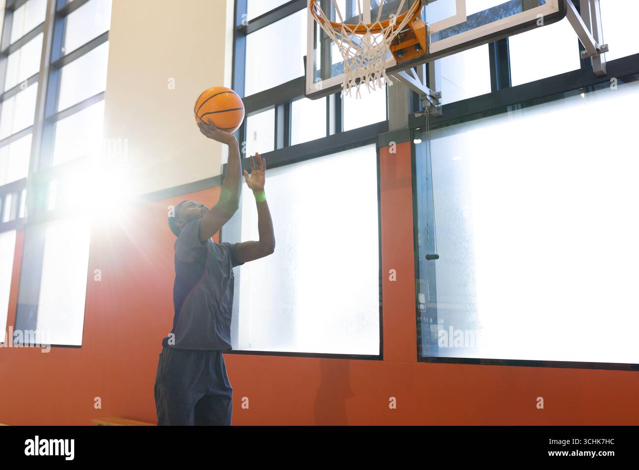 Mann in Sportswear, der auf den Basketball springt und den Ball unter den Fenstern des Fitnessstudios hält, Kopierraum Stockfoto