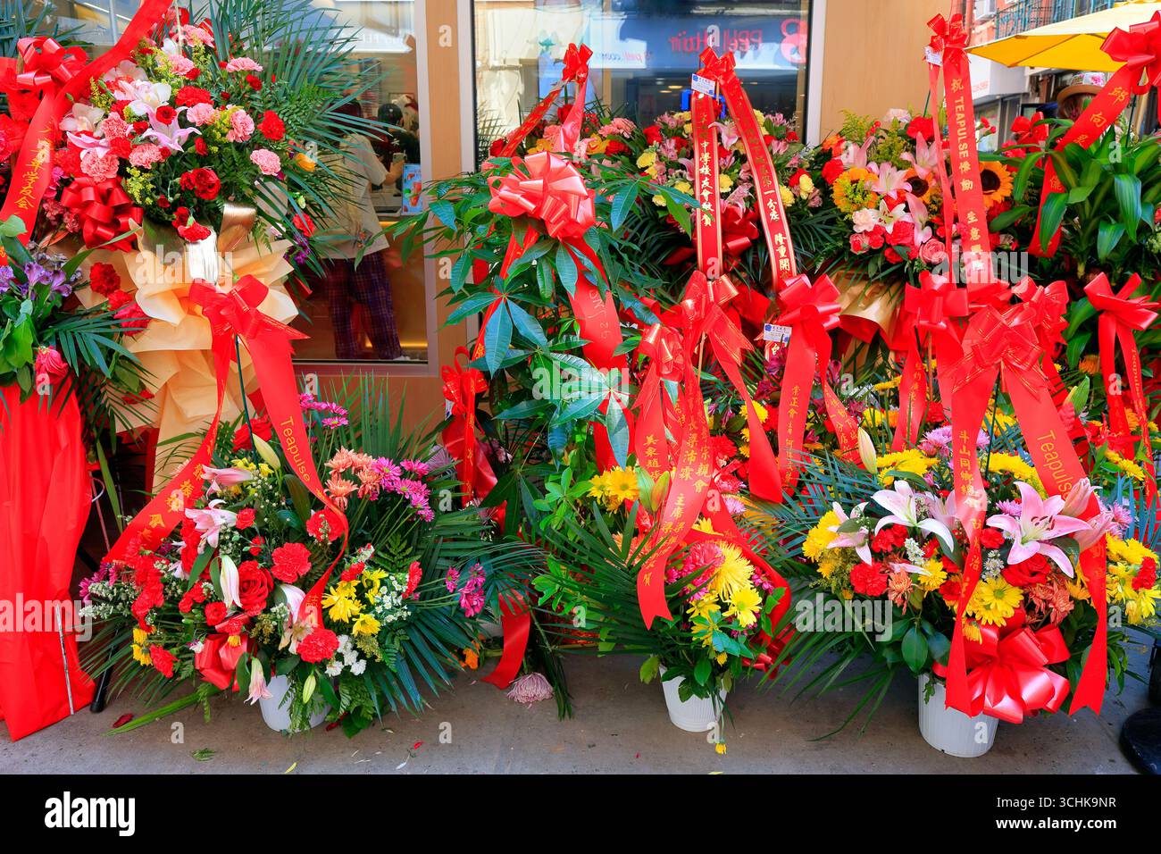 Feierliche rote Blumensträuße vor der großen Eröffnung eines Geschäfts in New York Chinatown. 開業花籃 Stockfoto