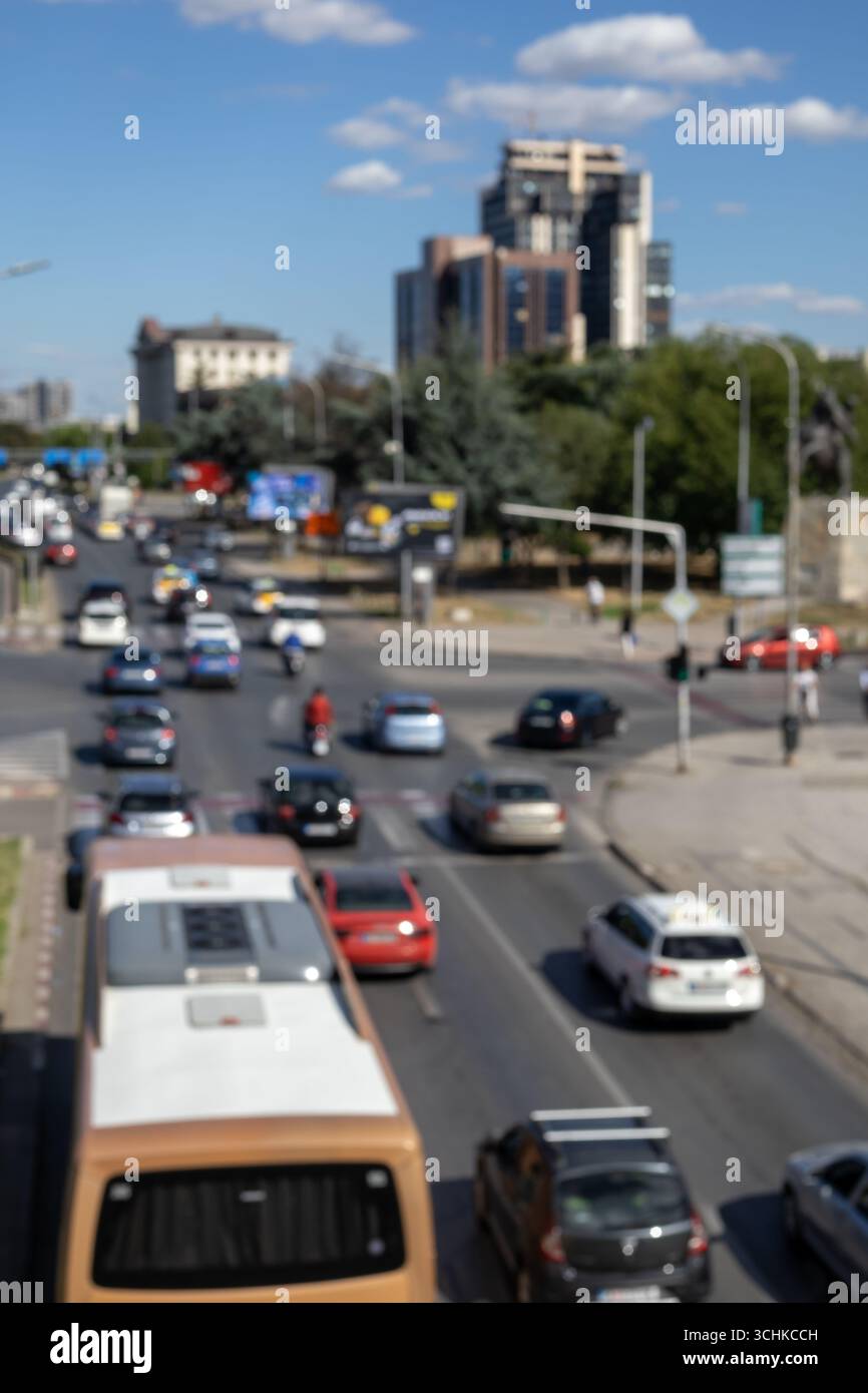 Eine verschwommene, hochwinkelige und vertikale Aufnahme einer belebten Stadtstraße mit einem Bus und verschiedenen Autos. Das Bild erfasst die dynamische, verschwommene Bewegung der täglichen tr Stockfoto