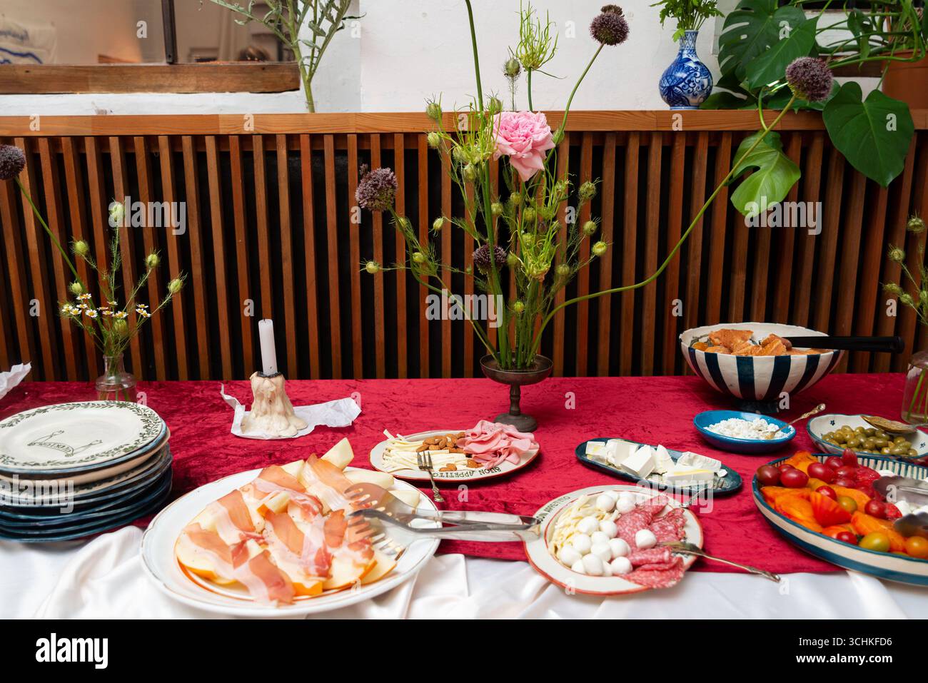 Der elegant gestaltete Tisch bietet verschiedene Vorspeisen wie Aufschnitt, Käse und Gemüse. Die Einrichtung umfasst Blumendekorationen und feine Ta Stockfoto