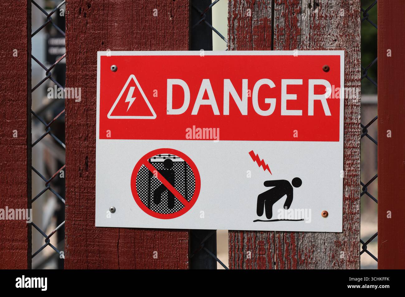 Warnschild für Stromschlaggefahr in Nahaufnahme auf rotem Holzzaun Stockfoto Warnschild für Stromschlaggefahr in Nahaufnahme auf rotem Holzzaun Stockfoto