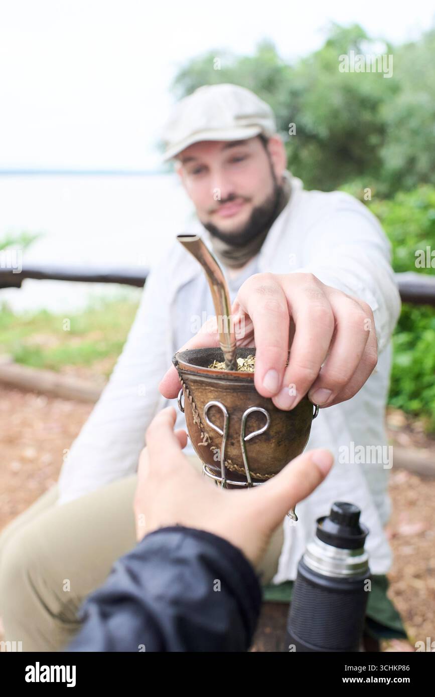 Mann teilt sich mit jemandem einen Partner. Dieser argentinische Aufguss ist ein Symbol für das Teilen und Zusammensein. Komposition mit selektivem Fokus auf die Hände. Stockfoto