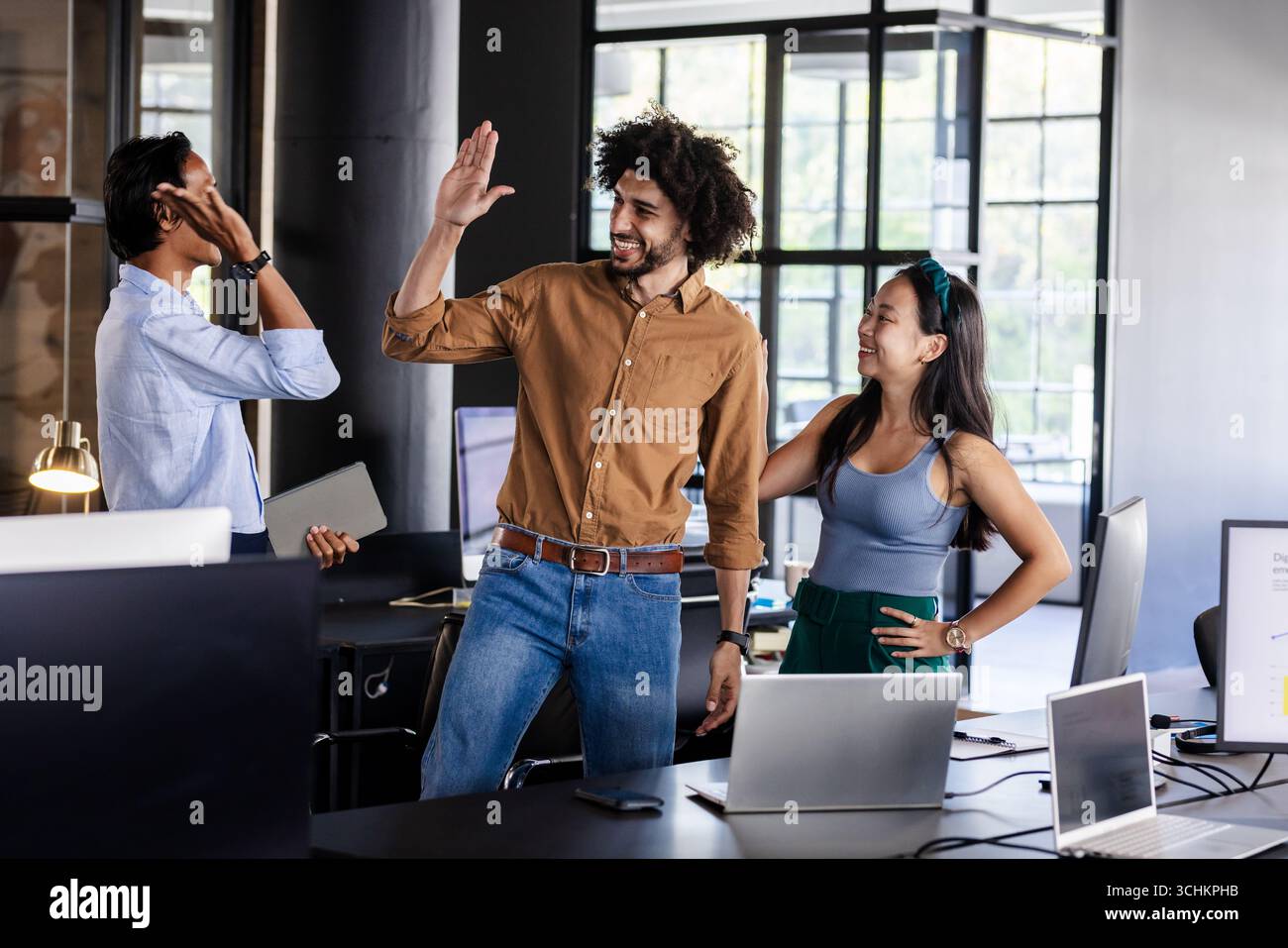 Vielseitiges Business-Team feiert Erfolge mit High Five in modernen Büros Stockfoto