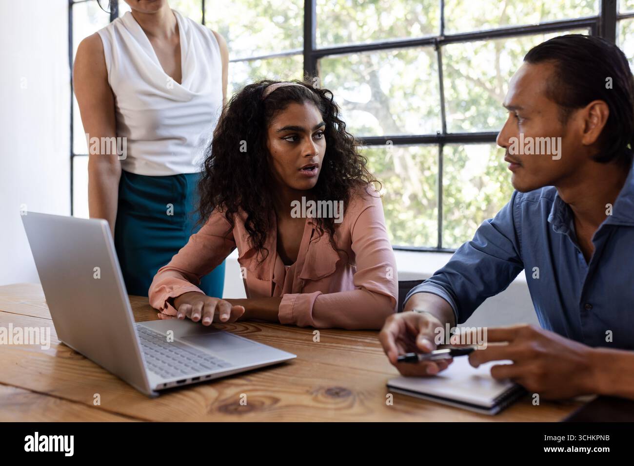 Diverse Geschäftsteams diskutieren das Projekt am Bürotisch mit Laptop und Notizblock Stockfoto