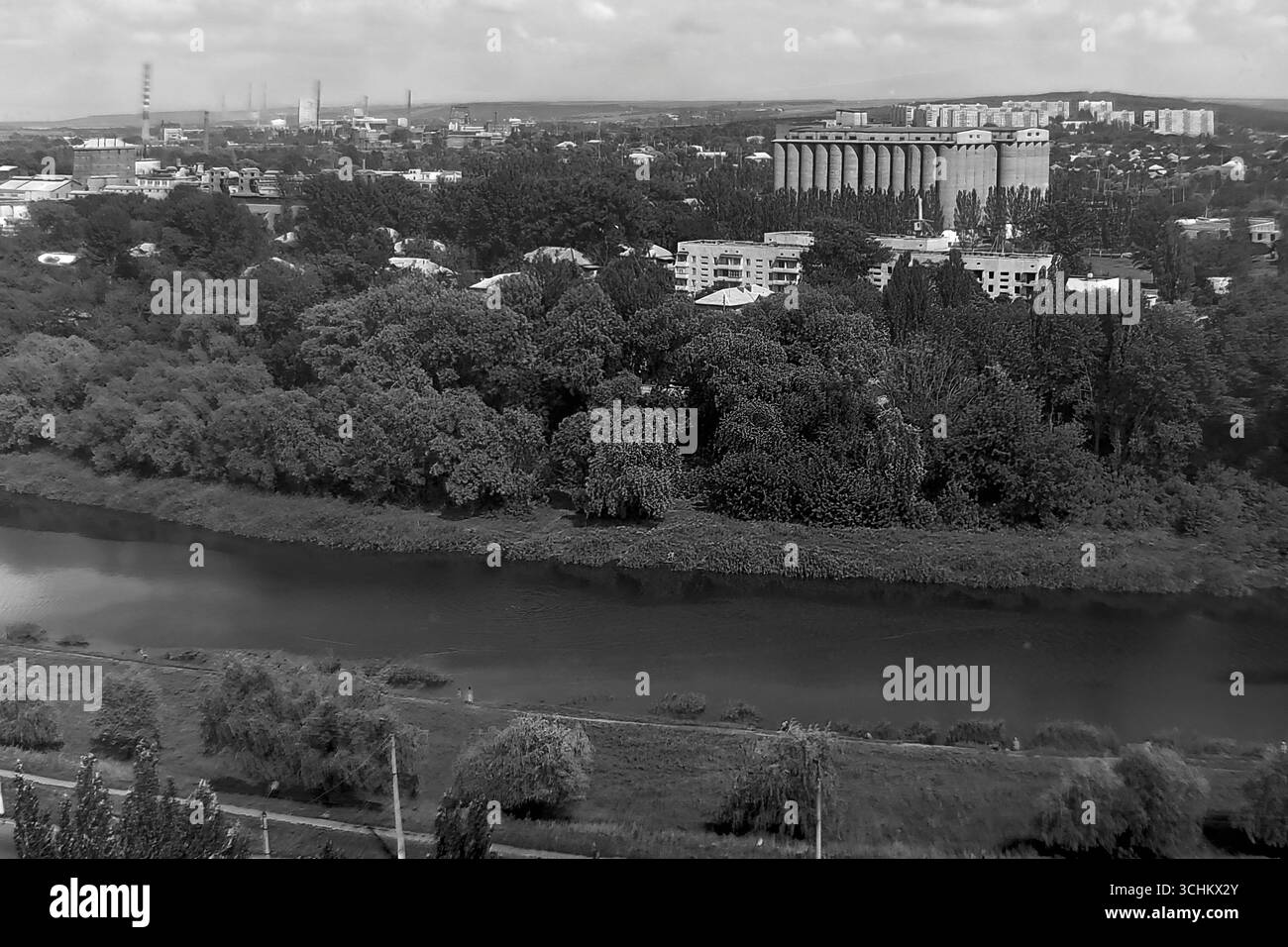 Ein Schwarzweißfoto aus dem Archiv, das im Juli 1997 in Sloviansk aufgenommen wurde. Ein Panoramablick über den Fluss Kazennyi Torets und das Industriegebiet der Stadt. Der Rahmen wird von einem massiven Kornelevator dominiert, einem wichtigen Teil der agroindustriellen Infrastruktur von Sloviansk. Die Landschaft spiegelt die wirtschaftliche Grundlage der Region wider und verbindet Industrie und Landwirtschaft Stockfoto