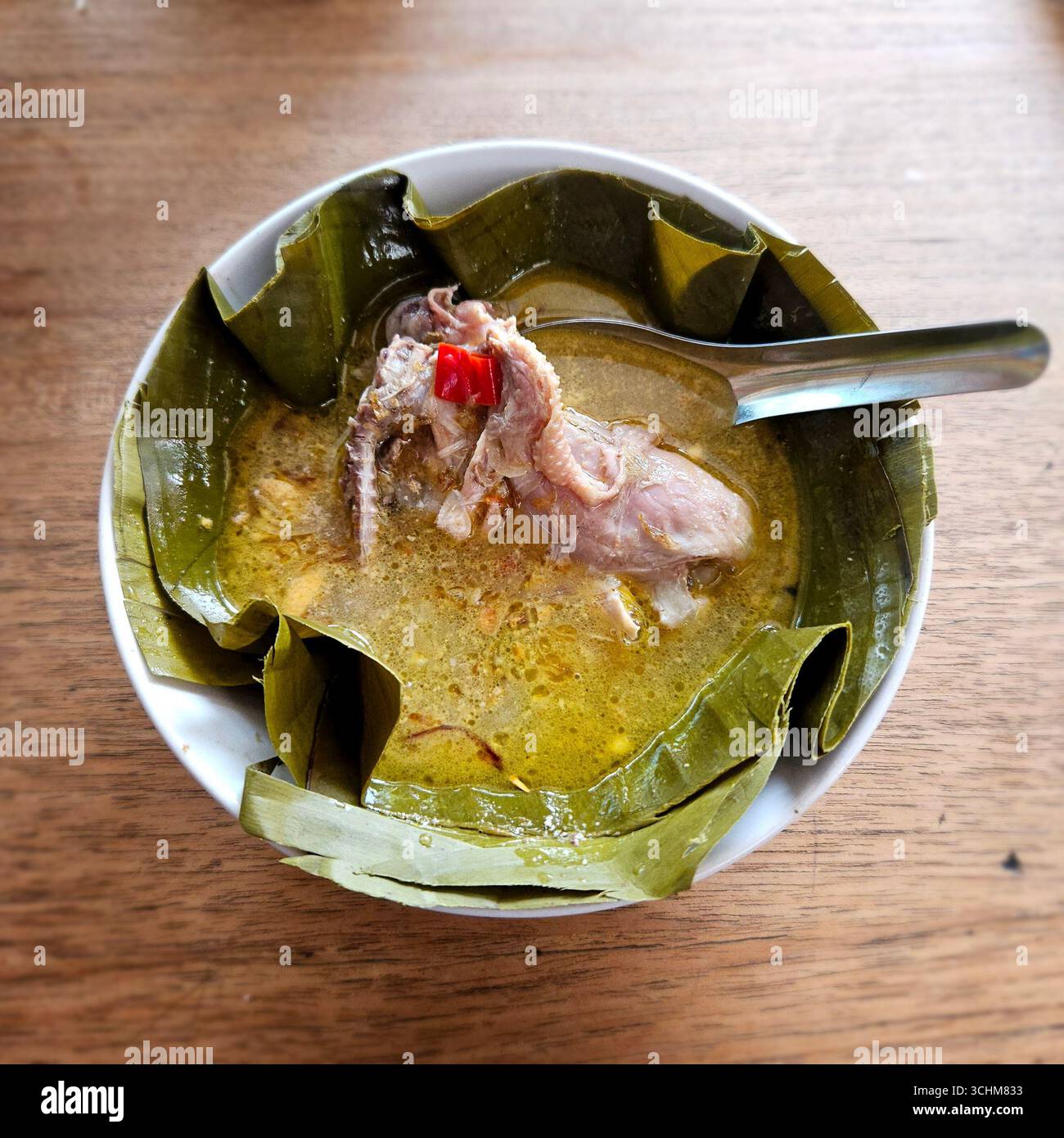 Traditionelle indonesische Hühnersuppe mit reichhaltiger Brühe, Kräutern und Gewürzen, serviert in einer weißen Schüssel, authentische asiatische Küche - Smartphone-aufgenommenes Stockfoto