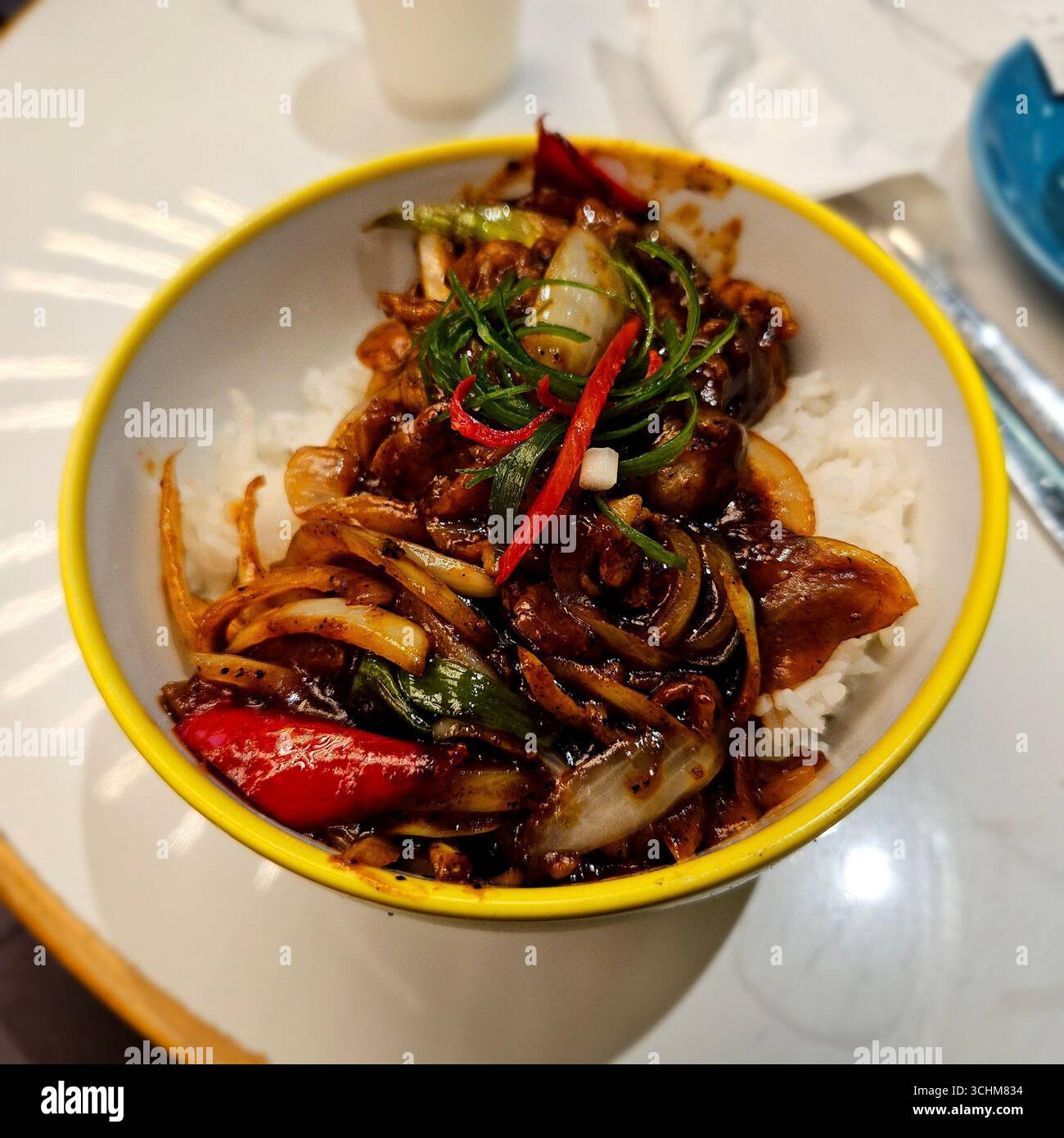 Herzhaftes Rindfleisch mit schwarzem Pfeffer-Rührbraten mit Zwiebeln und Chili, serviert auf Teller, aromatische asiatische Küche mit reichhaltigem Geschmack und bunten Zutaten - Smartphone-aufgenommenes Stockfoto