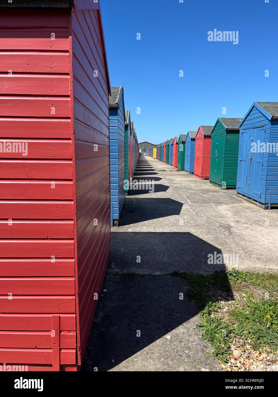 Fluchtpunkt-Aufnahme von farbenfrohen Strandhütten mit starken Schatten, St. Leonards-on-Sea - Smartphone-aufgenommenes Stockfoto