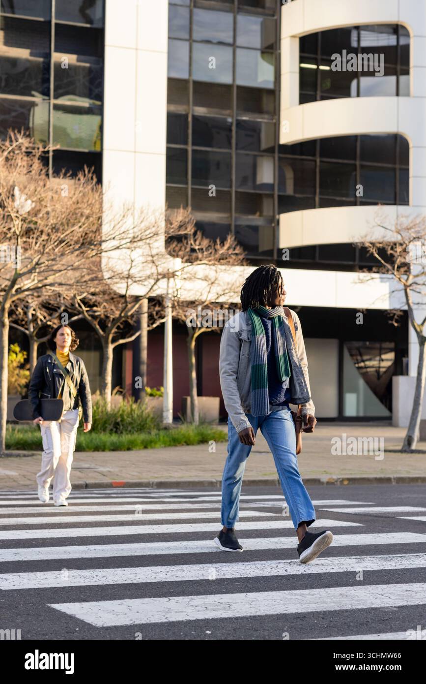 Verschiedene Fußgänger, die auf einem Zebraübergang am Büro vorbeilaufen, tragen Tragetasche und Handtasche Stockfoto