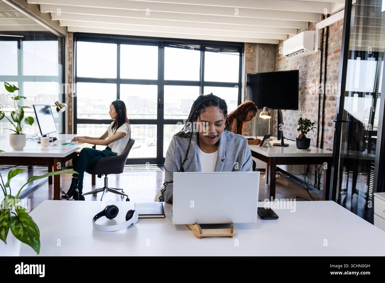 Frau, die im modernen Büro an einem Laptop arbeitet, konzentriert und produktiv Stockfoto