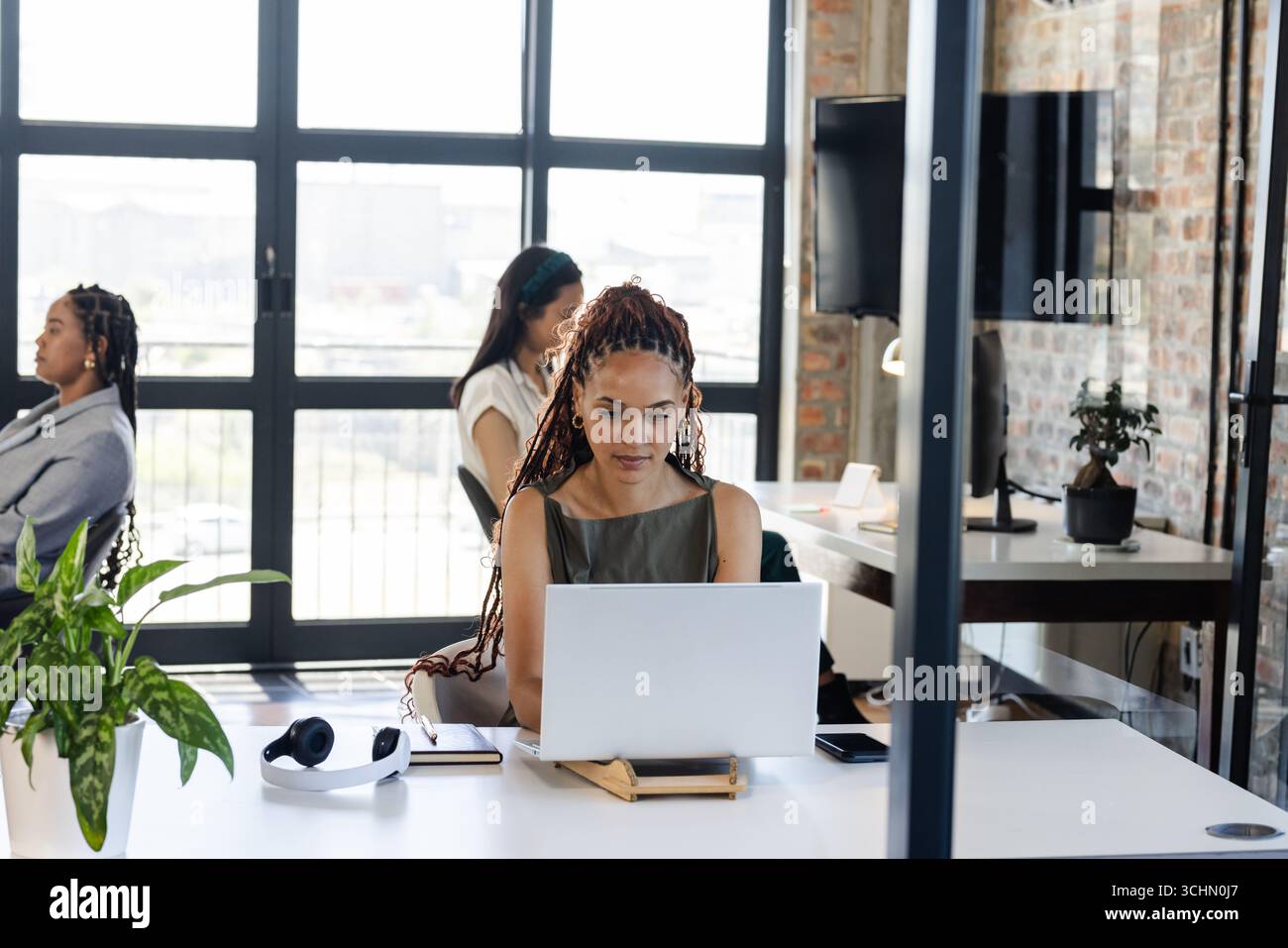 Frau, die im modernen Büro an einem Laptop arbeitet, konzentriert und produktiv Stockfoto