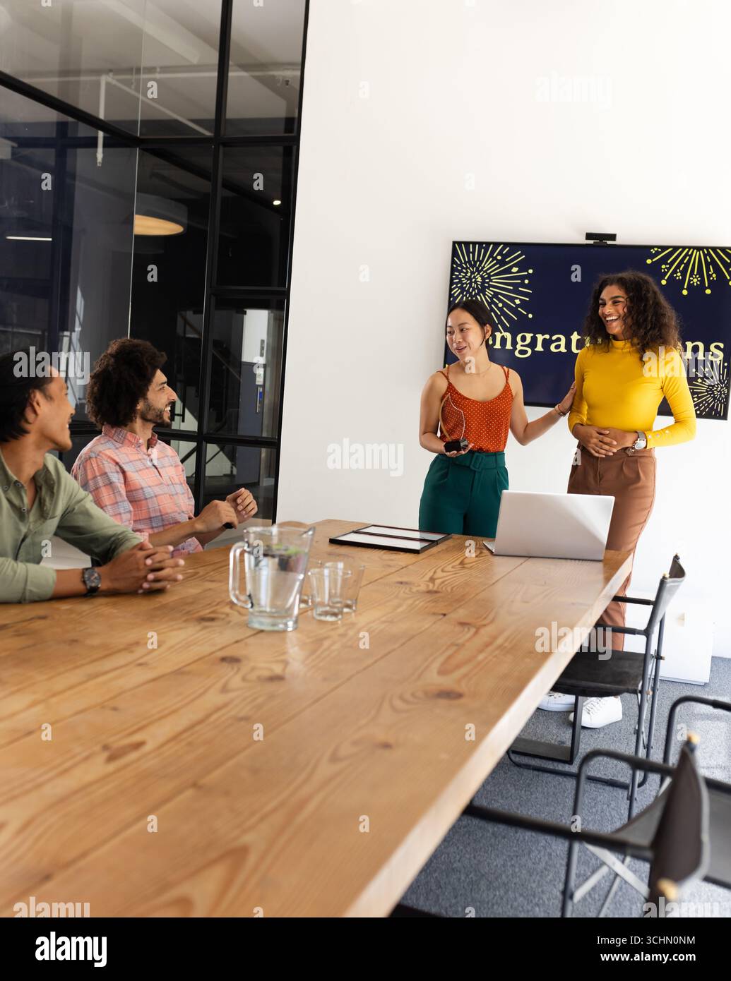 Vielseitiges Business-Team feiert Erfolg im modernen Konferenzraum mit Laptop, im Büro Stockfoto