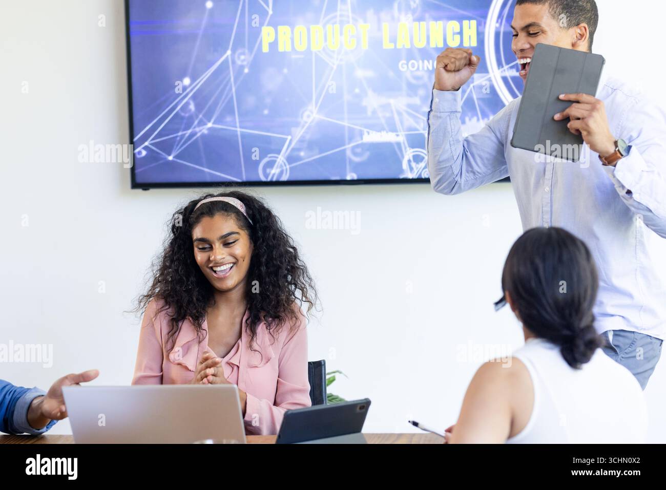 Ein vielfältiges Team feiert erfolgreiche Produkteinführung in einem modernen Büro-Besprechungsraum Stockfoto