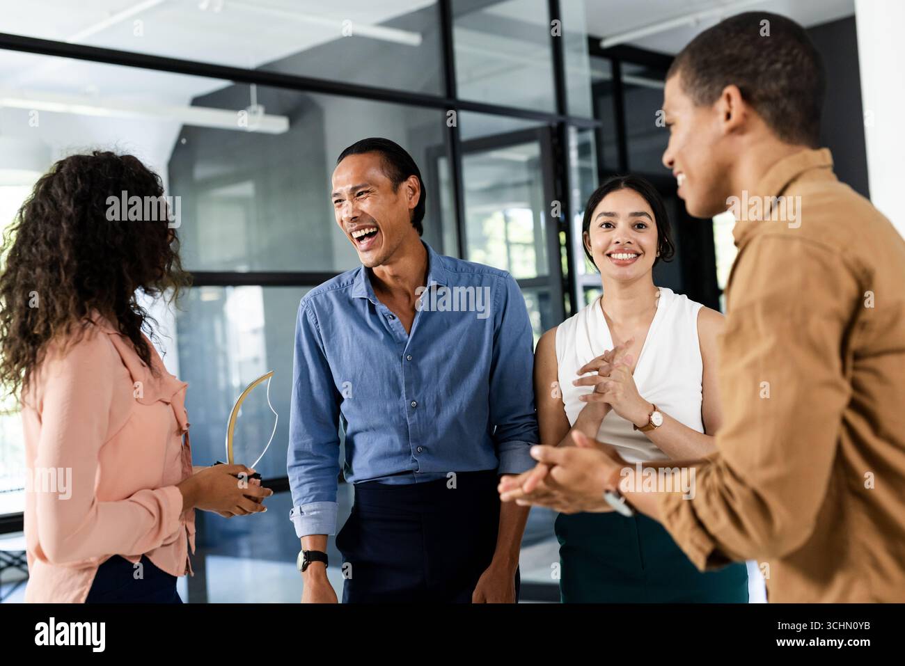 Erfolg feiern, vielseitiges Business Team lacht und applaudiert im modernen Büro Stockfoto
