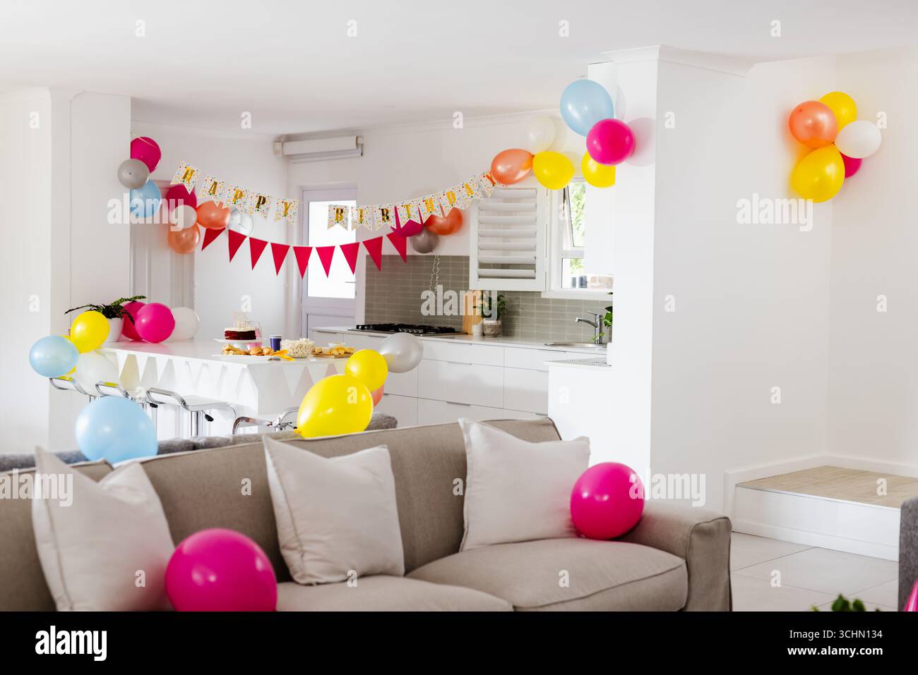 Zu Hause schmücken bunte Ballons und Geburtstagsbanner die moderne Küche zum Feiern Stockfoto