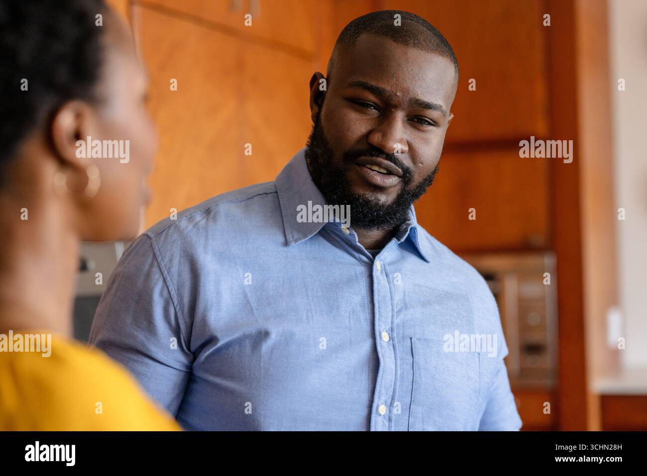 Mann in blauem Hemd, der zu Hause Gespräche führt und Interesse bekundet Stockfoto