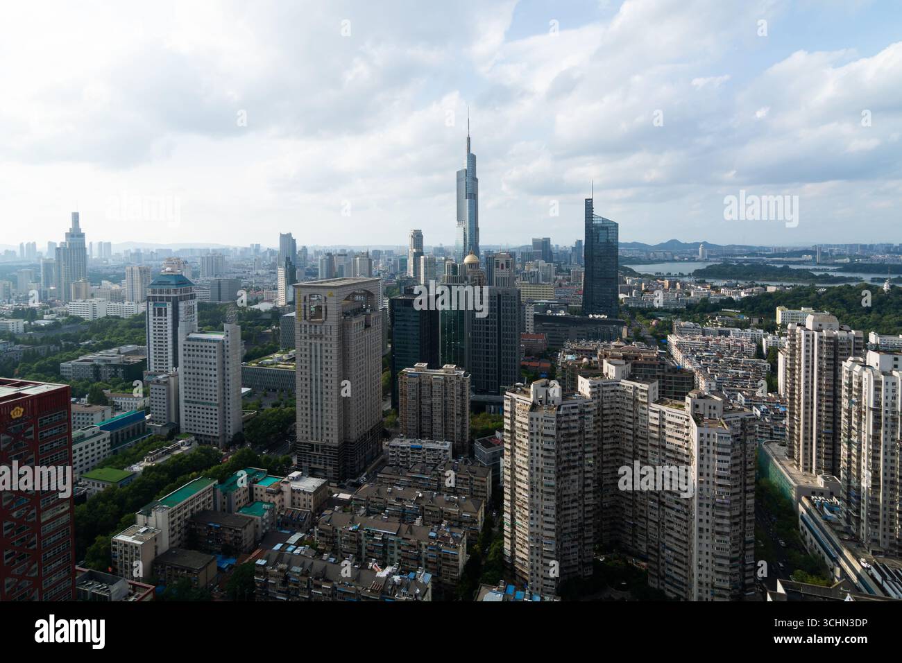 Aus der Vogelperspektive auf eine dichte Skyline der Stadt mit einem markanten Wolkenkratzer, einem fernen See und Bergen unter einem bewölkten Himmel. Stockfoto