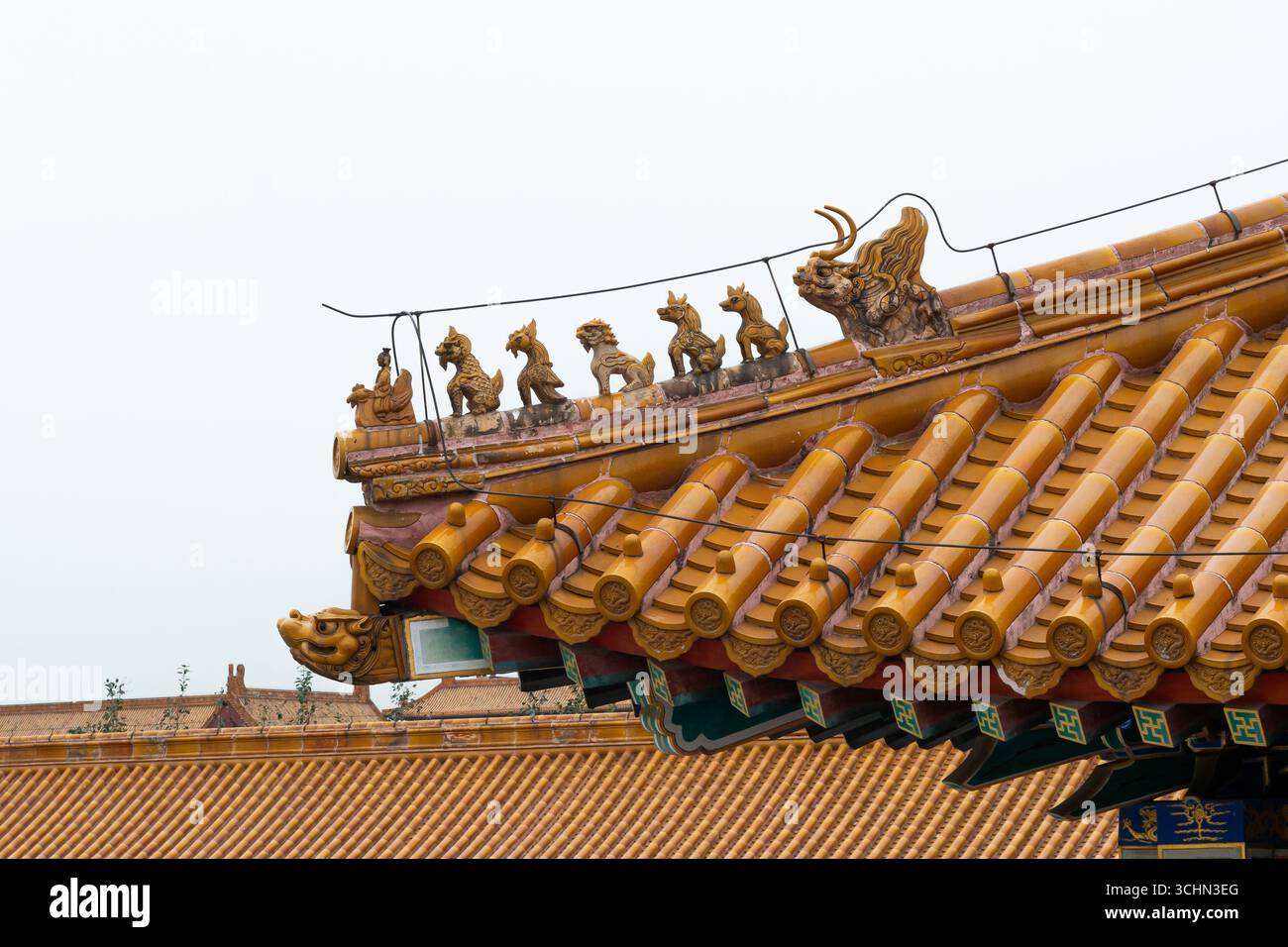 Nahaufnahme eines traditionellen chinesischen Daches mit gelb glasierten Fliesen und einer Reihe von mythischen Schutzfiguren auf der Traufe. Stockfoto
