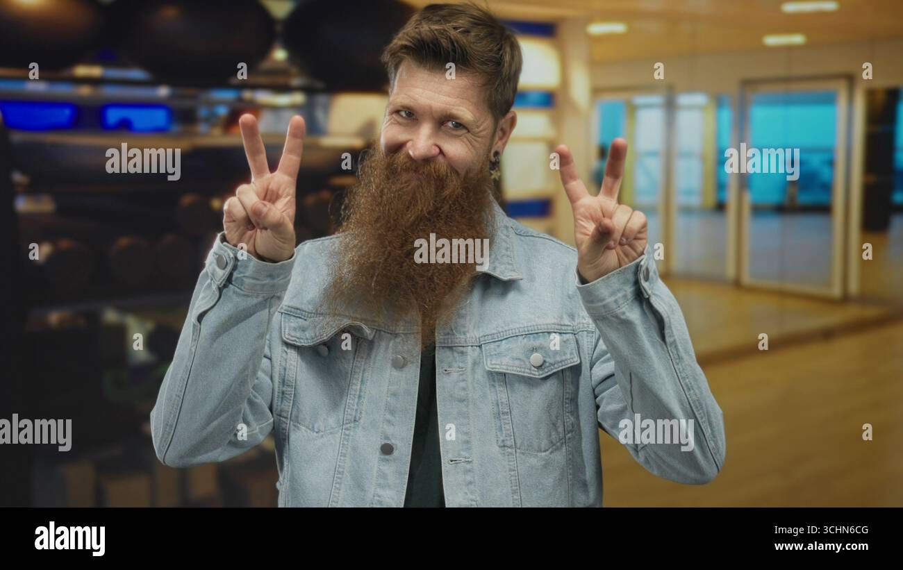 Junger Mann, der Zitate im Fitnessraum in einem Fitnessgebäude mit Gewichthängen und Übungsbälle macht; Ironie. Stockfoto