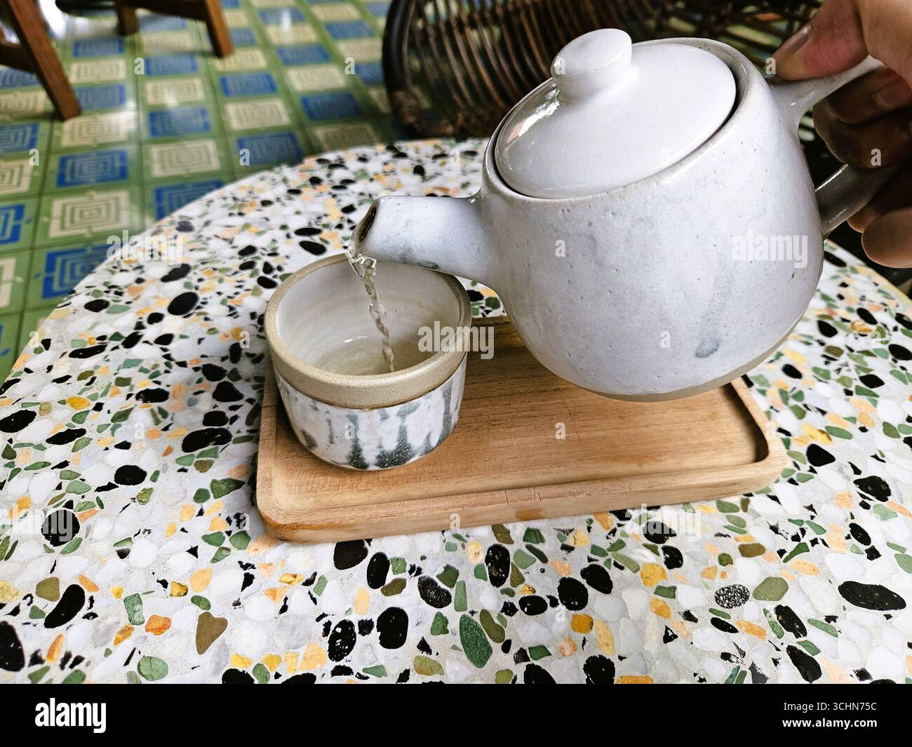 Weiße Keramik-Teekanne mit Tasse auf Holztablett, einfacher Tee bei Tageslicht - Smartphone-aufgenommenes Stockfoto