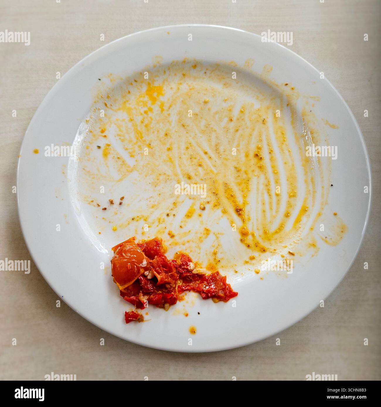 Leere weiße Platte mit Resten und Chili-Sauce, Symbol für fertige Mahlzeit - Smartphone-aufgenommenes Stockfoto
