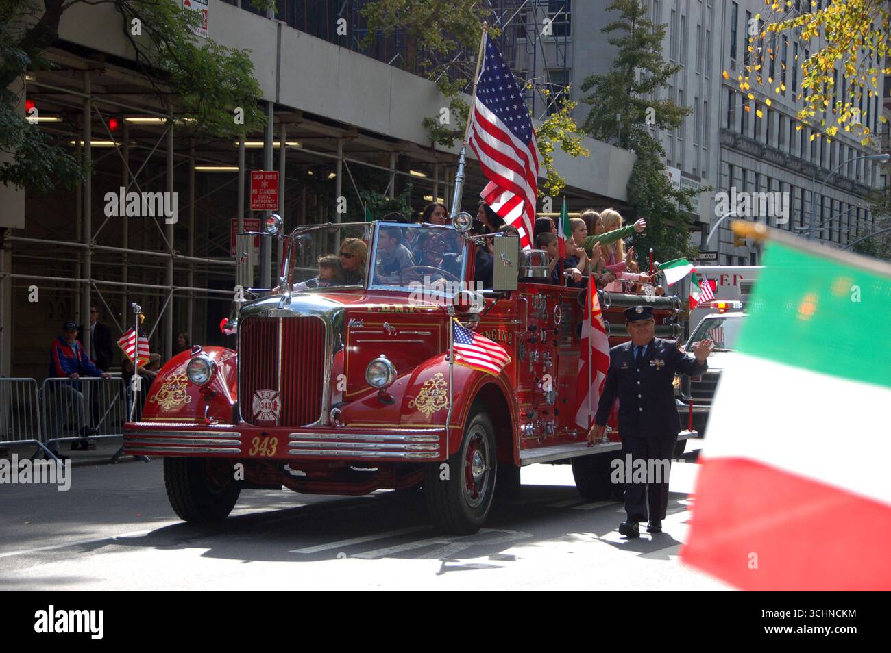 Roter Feuerwehrwagen mit amerikanischen und italienischen Flaggen während der Columbus Day Parade in New York City, der die Menschen bei festlichen Feierlichkeiten mitnimmt Stockfoto
