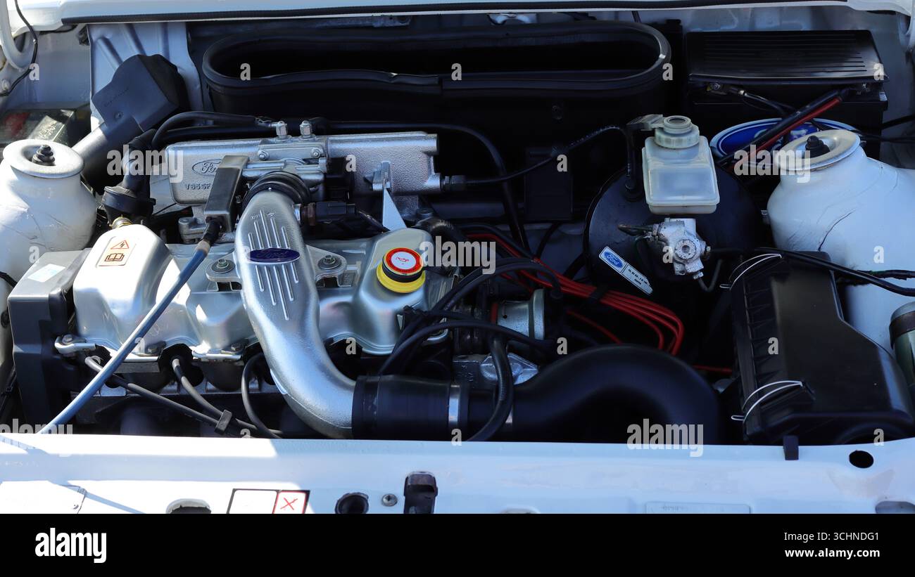 Diese Abbildung zeigt eine Nahaufnahme des Motorraums eines weißen Ford Escort RS Turbo. Der Motor ist sauber und gepflegt und verfügt über einen auffälligen silbernen Ansaugkrümmer. Das Auto, eine klassische Heißluke aus den 80er Jahren, ist auf der Stokes Bay Car Rallye zu sehen. Illustrativ, Editorial: Die Stokes Bay Car Rally in Gosport, Hampshire, England. 25. August 2025. Stockfoto