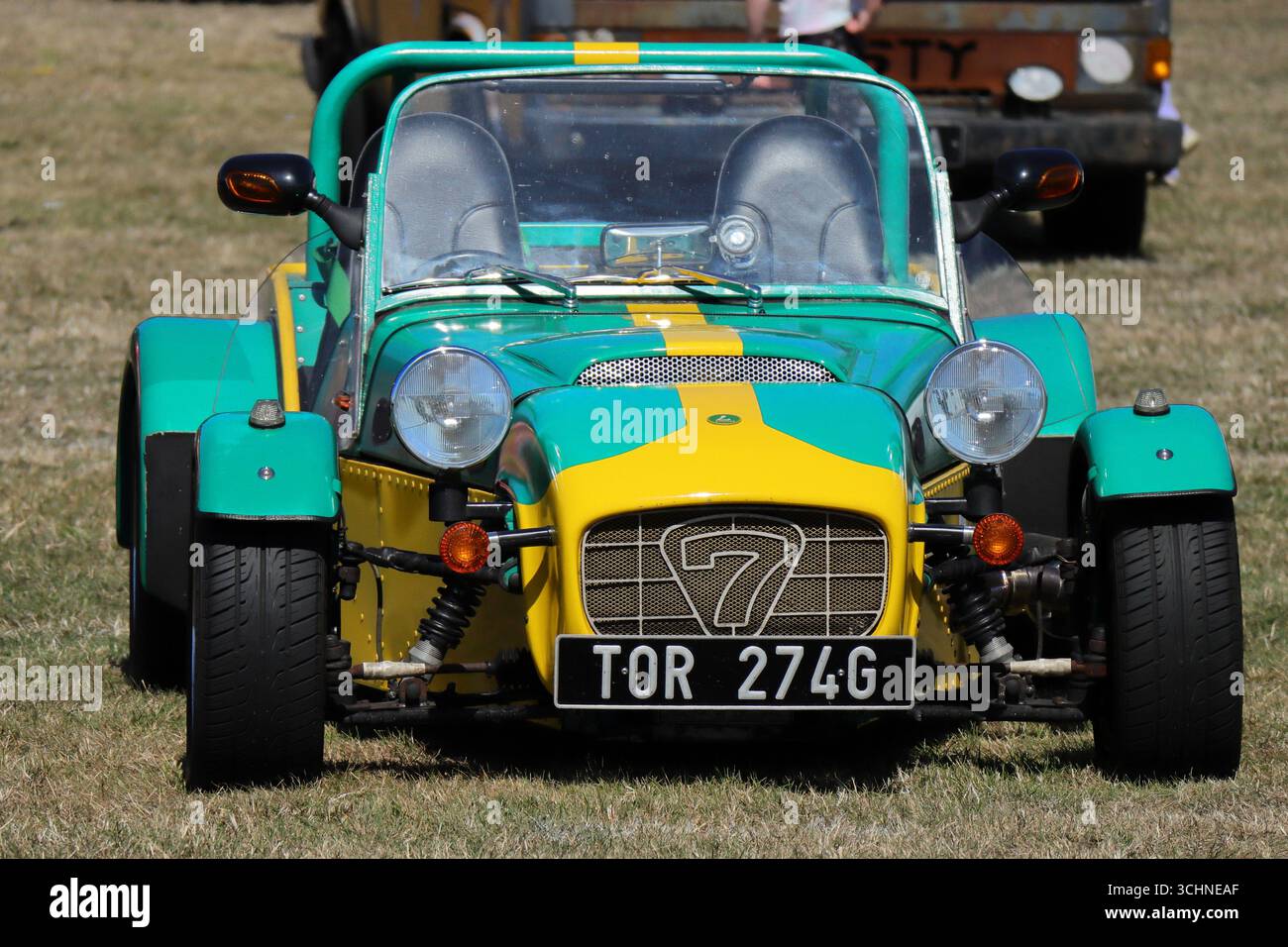 Illustrativ, Editorial: Die Stokes Bay Car Rally in Gosport, Hampshire, England. 25. August 2025. Ein leuchtend grün-gelbes Kit Car, eine Nachbildung eines klassischen Lotus Seven, ist von der Vorderseite zu sehen. Die Motorhaube hat einen Rennstreifen und die Nummer „7“ auf dem Kühlergrill. Er wird auf einem grasbewachsenen Feld mit anderen Fahrzeugen im Hintergrund geparkt. Stockfoto