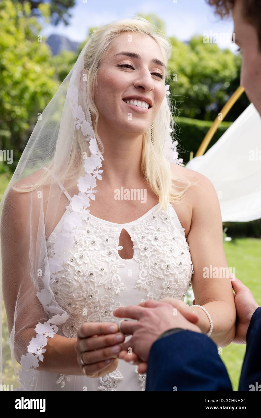 Die Braut lächelt fröhlich, während sie während der Hochzeitszeremonie im Freien Gelübde austauscht Stockfoto